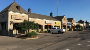 A retail shopping center with several tenants viewed from the parking lot.