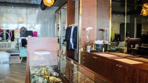 A display case in a clothing store with a hanging light fixture overhead and clothes hanging in the background