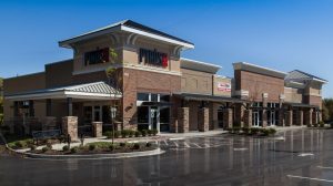 The exterior of a restaurant called Pyro's in a shopping center. The logo is above the main entrance and the parking lot is empty.