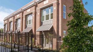 The exterior view of a two story apartment building with a metal fence around the outside