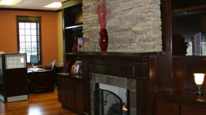 A fireplace in the open space of a bank with an office in the background.