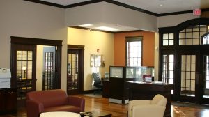 The interior waiting area of a bank with several seating options and a desk in the back corner.