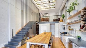 Open, modern kitchen with a dining room table in the center and stairs leading to the second level