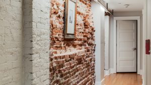 Hallway with exposed brick walls leading to another room