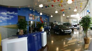 The lobby of a Ford dealership, featuring the receptionist's desk and two cars parked behind on it on display.