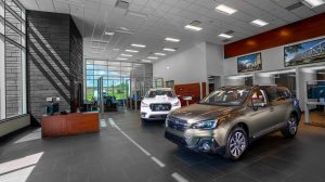 A car dealership lobby with two cars parked inside on display and a desk directly as you enter.