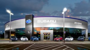 A Subaru dealership lit at night with cars parked on display out front.