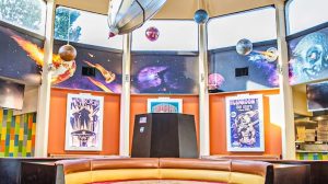 A restaurant booth with a space ship and planets hanging from the ceiling