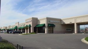An outdoor shopping center with a drive through and green awnings